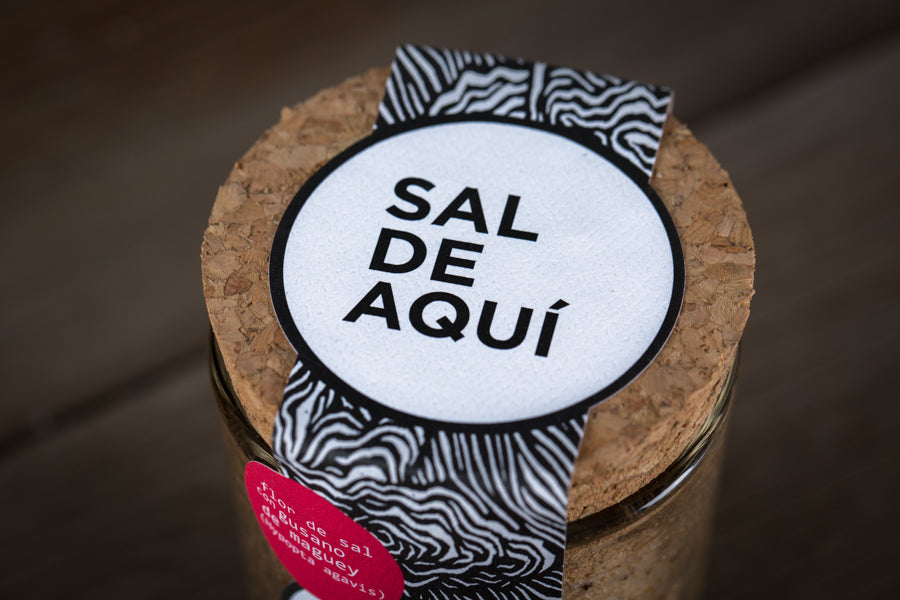
                  
                    Logo Sal de Aquí sobre base de madera – sal artesanal mexicana con gusano de maguey ingrediente prehispánico
                  
                
